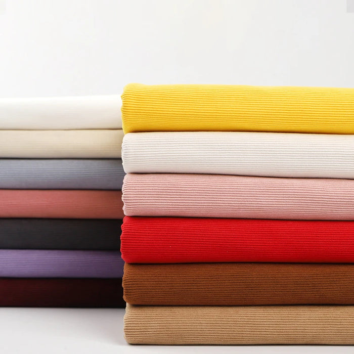 A neatly stacked pile of Longan Craft 16 Wales Fine Wale Corduroy Fabric in solid yellow, white, pink, red, brown, gray, and purple—perfect for DIY sofa covers, clothing, and pants—is displayed against a plain white background.