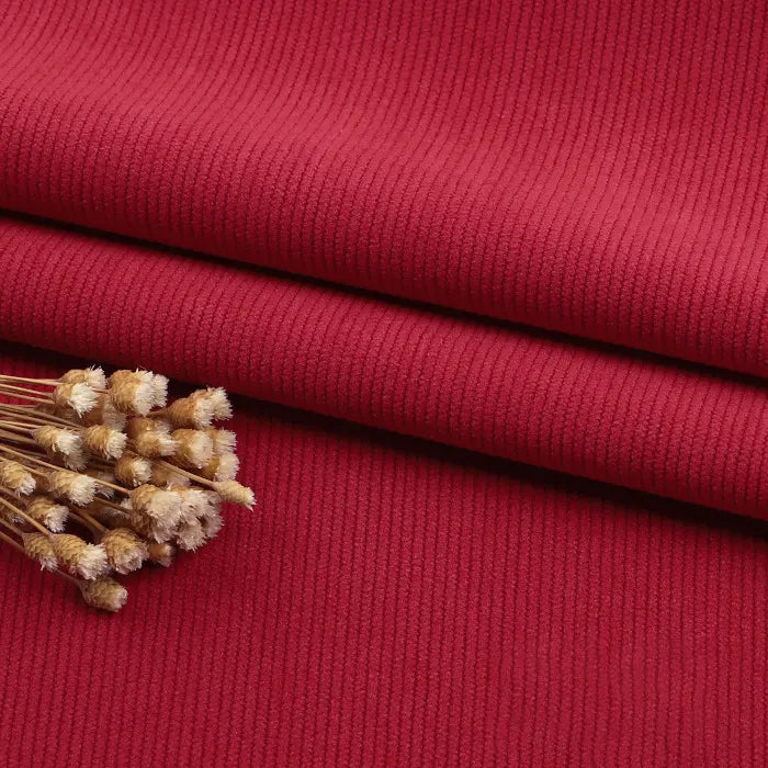 A close-up of Longan Craft Fine Wale Corduroy Material By The Yard in solid red, with a small bunch of dried beige flowers on top—perfect DIY fabric for sofa, clothing, or pants.