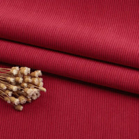 A close-up of Longan Craft Fine Wale Corduroy Material By The Yard in solid red, with a small bunch of dried beige flowers on top—perfect DIY fabric for sofa, clothing, or pants.