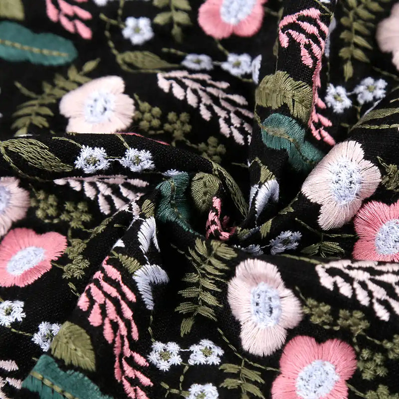 Close-up of Longon Craft’s Floral Cotton Linen Embroidered Fabric by the yard in black, featuring detailed multicolor flower embroidery on cotton linen, ideal for dressmaking and crafts.