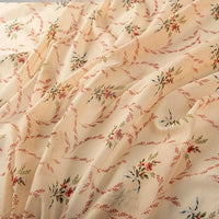 A close-up of Longan Craft’s Floral Digital Print Voile Fabric By The Yard, a lightweight, breathable cotton voile with a soft feel and slightly sheer finish. Features a delicate red, green, and yellow floral and vine pattern in a diagonal design.