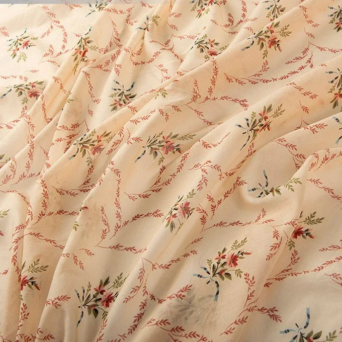 A close-up of Longan Craft’s Floral Digital Print Voile Fabric By The Yard, a lightweight, breathable cotton voile with a soft feel and slightly sheer finish. Features a delicate red, green, and yellow floral and vine pattern in a diagonal design.