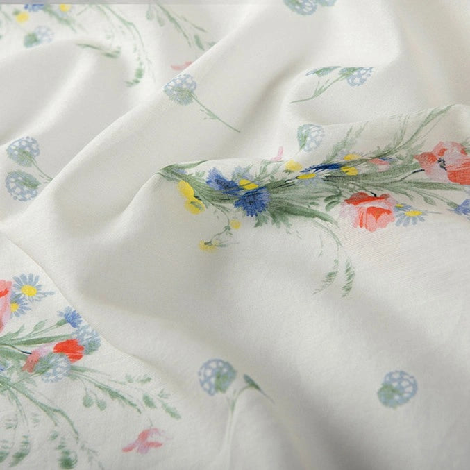 A close-up of Longan Craft Floral Digital Print Voile Fabric by the Yard shows soft, lightweight cotton voile with a vibrant red, blue, and yellow floral print—perfectly breathable for airy tops and summer styles.