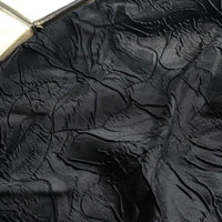 Close-up of Longon Craft's Floral Embossed Jacquard Brocade Fabric, featuring a 3D solid color flower pattern on black polyester with raised textures and subtle sheen—ideal for party costumes and tailored suits.