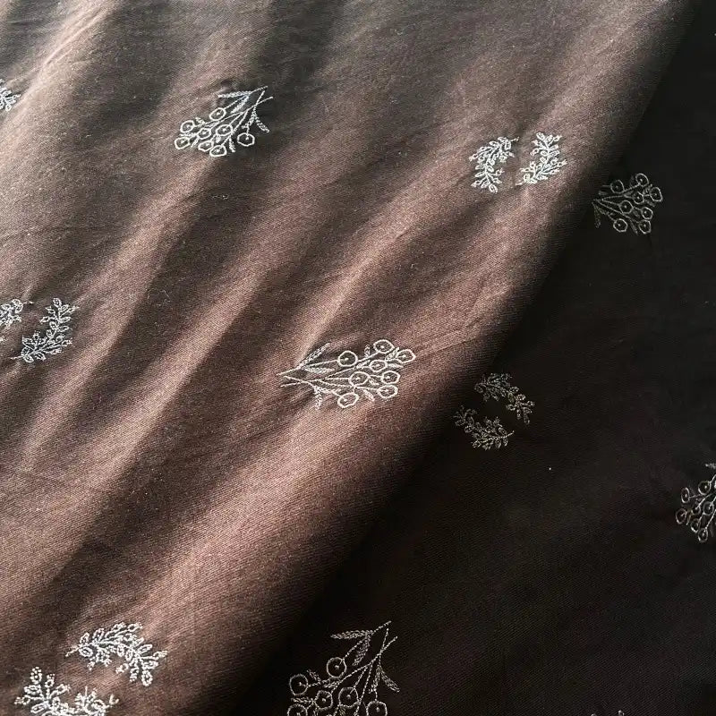 Longan Craft’s Floral Embroidered Cotton Corduroy Fabric By The Yard is a brown pinwale corduroy material with delicate white floral embroidery, featuring a rich texture and soft folds—ideal for autumn sewing projects.