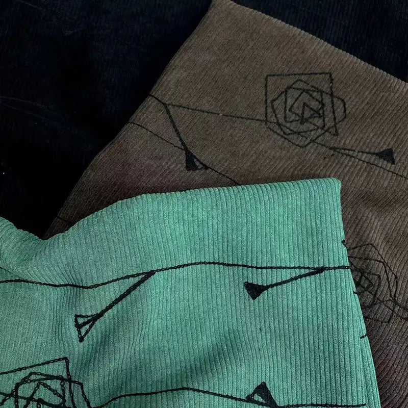 Close-up of Longan Craft Floral Embroidered Polyester Fine Wale Corduroy Fabric in teal, brown, and black, featuring a subtle line art pattern—ideal DIY textile for pants.