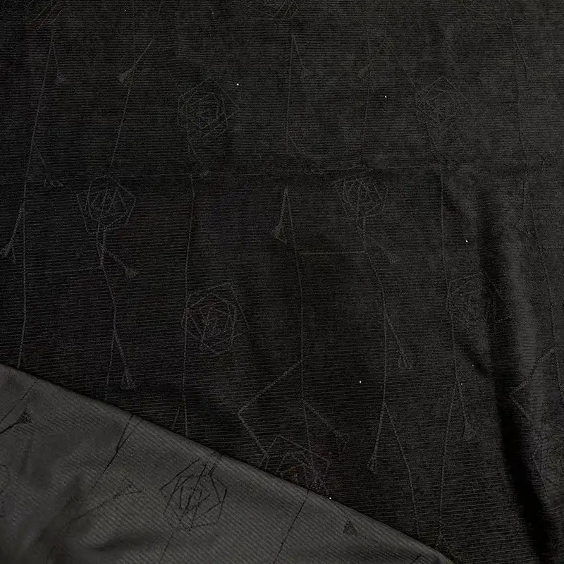 A close-up of Longan Craft’s Floral Embroidered Polyester Fine Wale Corduroy Fabric By The Yard shows subtle, slightly shiny patterns; one edge is folded to reveal the reverse side with a similar design. Ideal for DIY corduroy pants and textile projects.