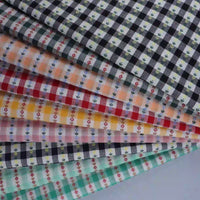 Explore the charming Floral Gingham Poplin Fabric By The Yard from Longan Craft—a collection of colorful cotton checkered jacquard poplin materials featuring gingham plaid patterns in shades of black, orange, yellow, red, and teal. Each piece is beautifully adorned with small floral designs and crafted from soft cotton fabric, making this perfect poplin fabric ideal for a range of creative garment-making and sewing projects.