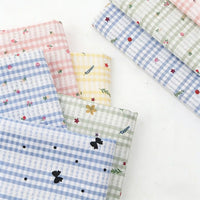 A selection of Longan Craft Floral Gingham Quilting Fabric by the Yard—polyester quilting material with botanical patterns—features overlapping pastel check and floral designs, displayed on a white surface.