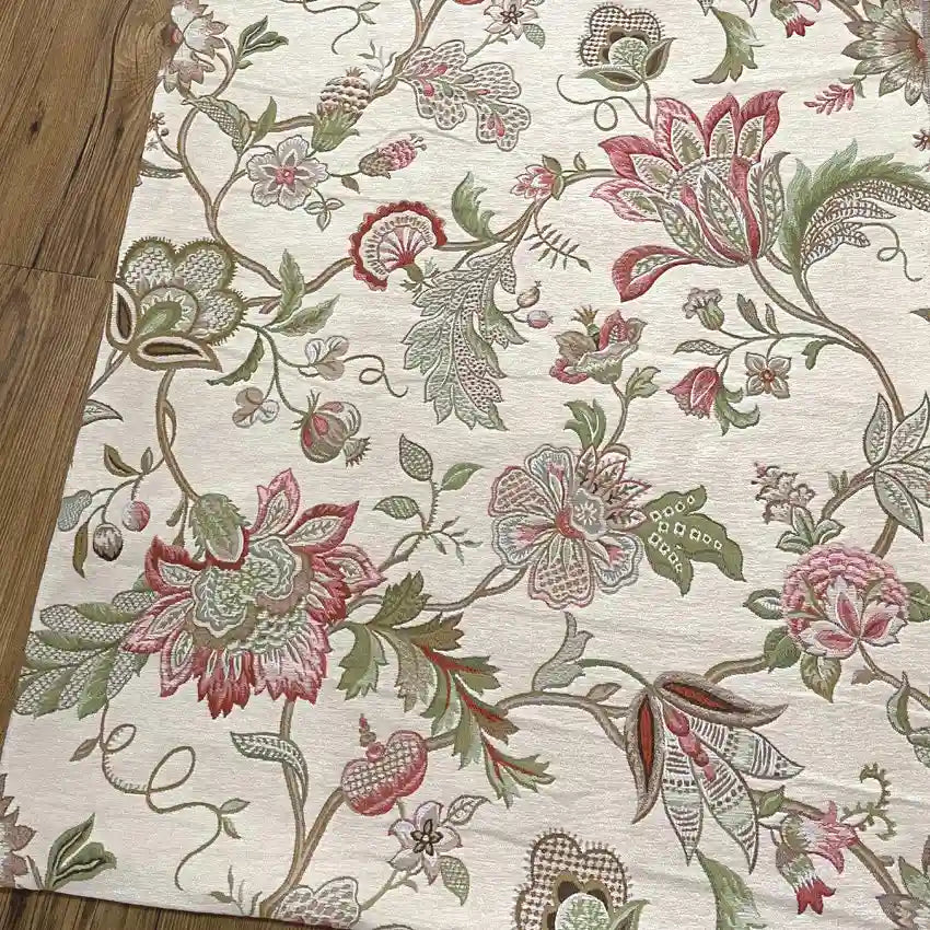 A close-up of Longan Craft's Floral Jacquard Chenille Fabric By The Yard shows its heavyweight poly chenille upholstery with an intricate pink, green, and beige floral pattern, large flowers, leaves, and vines on a cream background.