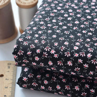 Two folded pieces of Longan Craft Floral Lawn Fabric By The Yard, a lightweight cotton with pink and white floral patterns, are shown beside a ruler and thread spools, ideal for breathable dressmaking or lining.