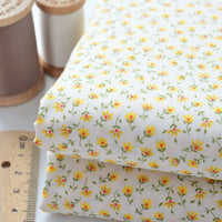 Two folded pieces of Longan Craft Floral Lawn Fabric By The Yard, lightweight cotton with a yellow and green floral print, shown with a ruler and beige/light brown thread—ideal for breathable dresses or cotton lawn projects.