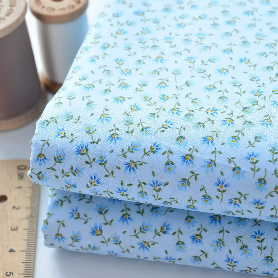 Longan Craft Floral Lawn Fabric By The Yard—lightweight blue cotton with a small blue and yellow floral pattern, shown with a ruler and spools of thread—is perfect as breathable dress or lining fabric.