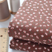 Floral Lawn Fabric By The Yard from Longan Craft, shown folded with a wooden ruler and brown thread. This lightweight cotton lawn fabric features a small white and pink floral print—ideal for breathable dress or lining projects.