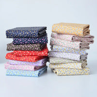 Two stacks of Longan Craft Floral Lawn Fabric By The Yard, featuring lightweight cotton in assorted floral colors and patterns, are arranged on a white surface against a light background. Perfect for lining or sewing projects.