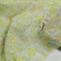 Longan Craft's Floral Prin Chiffon Silk Fabric By The Yard is a lightweight cotton silk material, featuring delicate yellow-orange flowers and green leaves on white—ideal for sheer curtains or elegant garments.
