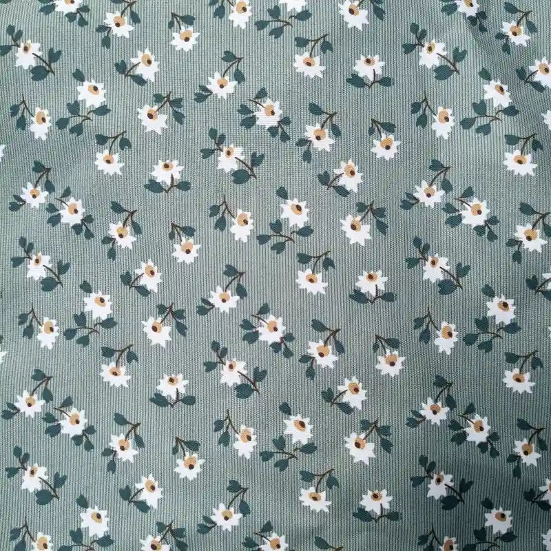 The Longan Craft Floral Printed Peachskin Fabric by the yard features small white flowers with yellow centers and green leaves on a muted green background, printed on soft microfiber polyester peachskin—ideal for comfy apparel projects.