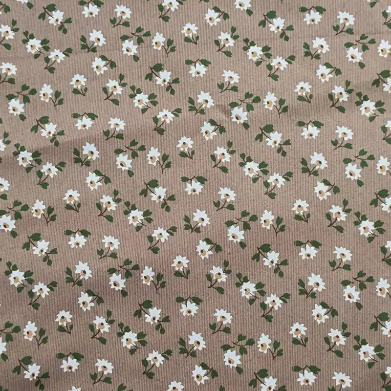 A close-up of Longan Craft’s Floral Printed Peachskin Fabric By The Yard reveals soft microfiber polyester with beige peachskin texture, featuring a repeating print of small white flowers with yellow centers and green leaves.