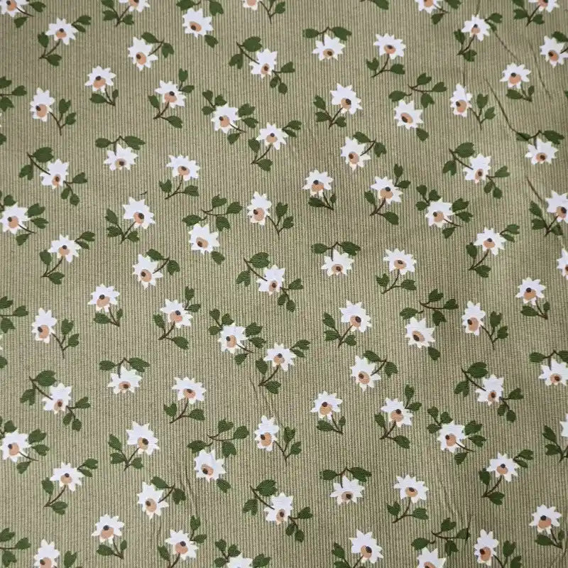 Longan Craft’s Floral Printed Peachskin Fabric By The Yard features a green background with small white flowers and yellow centers, printed on soft microfiber polyester peachskin—ideal for comfy apparel projects.