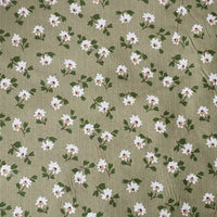 Longan Craft’s Floral Printed Peachskin Fabric By The Yard features a green background with small white flowers and yellow centers, printed on soft microfiber polyester peachskin—ideal for comfy apparel projects.