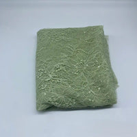 A folded piece of Floral Sequin Lace Fabric By The Yard from Longan Craft in light green, featuring a delicate floral pattern and sparkling sequins, displayed on white—ideal for dresses or elegant craft projects.