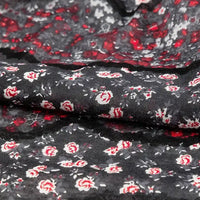 Close-up of Longan Craft Floral and Animal Printed Jersey Fabric—100% cotton with a floral pattern in red, white, and gray. The fabric appears slightly textured, loosely folded, and is perfect for dresses by the yard.