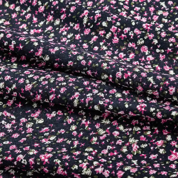A close-up of Longan Craft’s Floral and Animal Printed 100% Cotton Jersey Fabric by the Yard, showing clusters of pink, white, and green flowers on a slightly wrinkled surface—perfect jersey material for dresses.