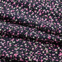 A close-up of Longan Craft’s Floral and Animal Printed 100% Cotton Jersey Fabric by the Yard, showing clusters of pink, white, and green flowers on a slightly wrinkled surface—perfect jersey material for dresses.
