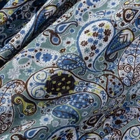 Close-up of Longan Craft Paisley Printed Jersey Fabric By The Yard, 100% cotton with a colorful blue, green, brown, and white paisley pattern featuring floral and geometric details. Slight wrinkles shown on the soft jersey fabric.