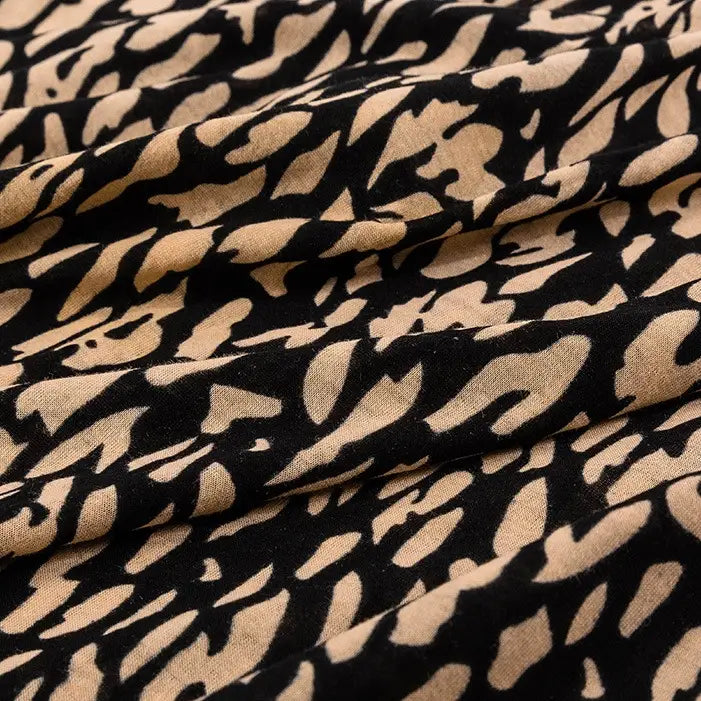 A close-up of Longan Craft's Floral and Animal Printed Jersey Fabric by the yard, made from 100% cotton jersey, shows abstract patterns with soft folds creating textured shadows—perfect for dresses and other jersey clothing projects.