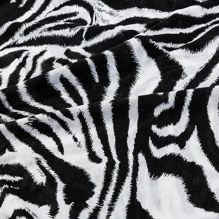 Close-up of Longan Craft’s Floral and Animal Printed 100% Cotton Jersey Fabric by the yard, featuring bold black and white zebra stripes with a soft, velvety texture—ideal jersey material for dresses and clothing.