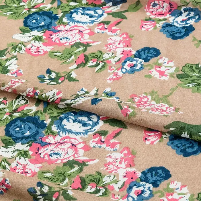 A close-up of Longan Craft's Floral and Animal Printed Jersey Fabric (100% cotton) displays its blue, pink, and white floral pattern with green leaves. This beige jersey fabric is ideal for dresses and sold by the yard.