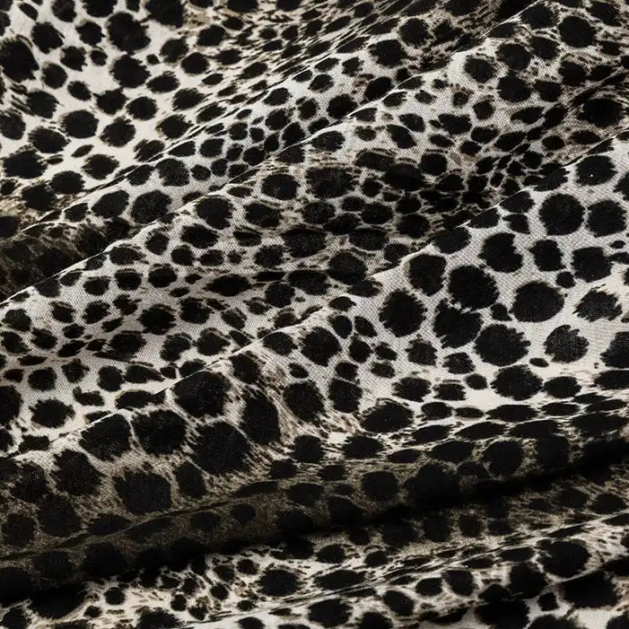 Close-up of Longan Craft’s 100% cotton Floral and Animal Printed Jersey Fabric by the yard, featuring a black and white animal print pattern. This soft jersey material is ideal for dresses and highlights natural folds and shadows.