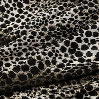 Close-up of Longan Craft’s 100% cotton Floral and Animal Printed Jersey Fabric by the yard, featuring a black and white animal print pattern. This soft jersey material is ideal for dresses and highlights natural folds and shadows.