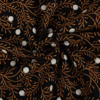 The Flower Embroidered Linen Fabric By The Yard from Longan craft features black linen with elegant floral embroidery, white dots, and brown leafy branches. This breathable sewing fabric is ideal for dresses and ensures comfort with stylish detail.