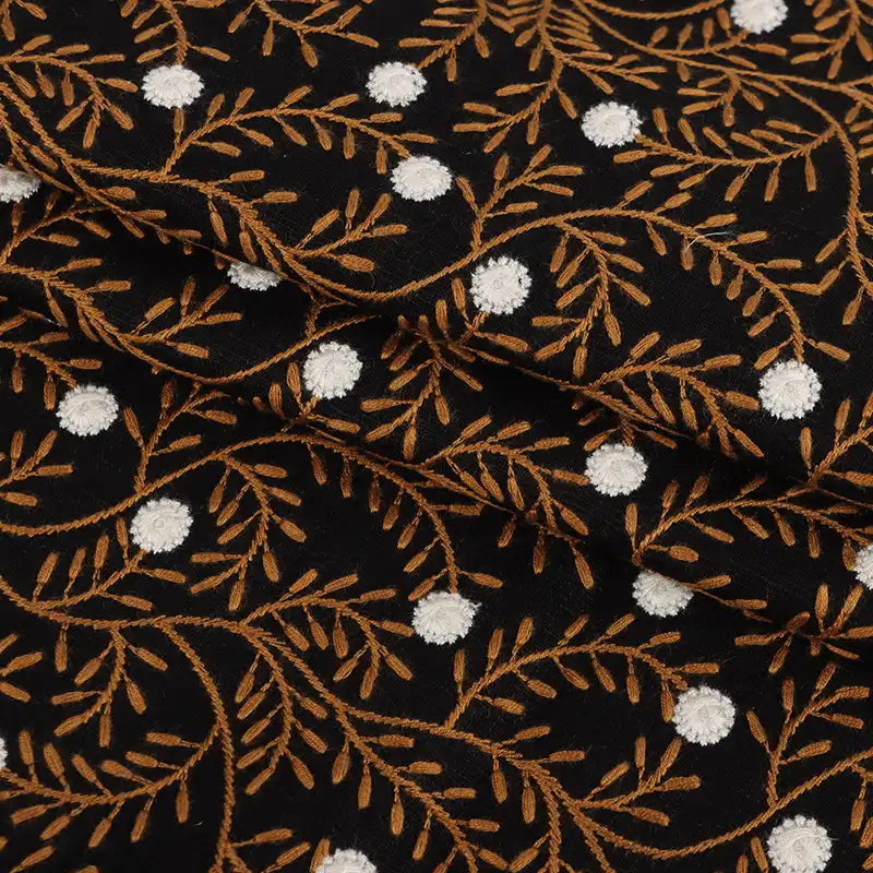 The Flower Embroidered Linen Fabric by Longan craft features black linen with floral embroidery, brown leafy branches, and small white accents. This breathable sewing fabric is ideal for dresses and is sold by the yard.