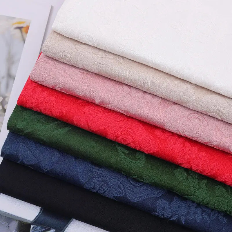 A stack of Flower Pattern Cotton Damask Fabric By The Yard from Longan Craft, featuring subtle chinoiserie floral jacquard designs—ideal damask weave material for tablecloths and décor.