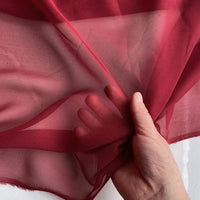 A hand holds up Longan Craft's Georgette Silk Fabric By The Yard, 8 Momme pure Mulberry silk crepe, highlighting its sheer, lightweight texture against a light background.