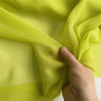 A hand gently pinches the Georgette Silk Fabric By The Yard by Longan Craft, showcasing the sheer, delicate texture of this 8 Momme pure mulberry silk crepe drapery fabric.