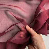 A hand displays Longan Craft's Georgette Silk Fabric By The Yard (8 Momme Pure Mulberry Silk Crepe), showing its sheer and delicate texture against a light background.