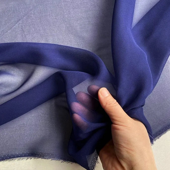 A hand holds a piece of Longan Craft Georgette Silk Fabric by the yard, 8 Momme pure mulberry silk crepe, revealing its soft, sheer texture against light.
