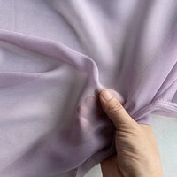 A hand gently holds and stretches Longan Craft’s Georgette Silk Fabric By The Yard—8 Momme Pure Mulberry Silk Crepe—highlighting its soft texture, drape, and sheer translucence.