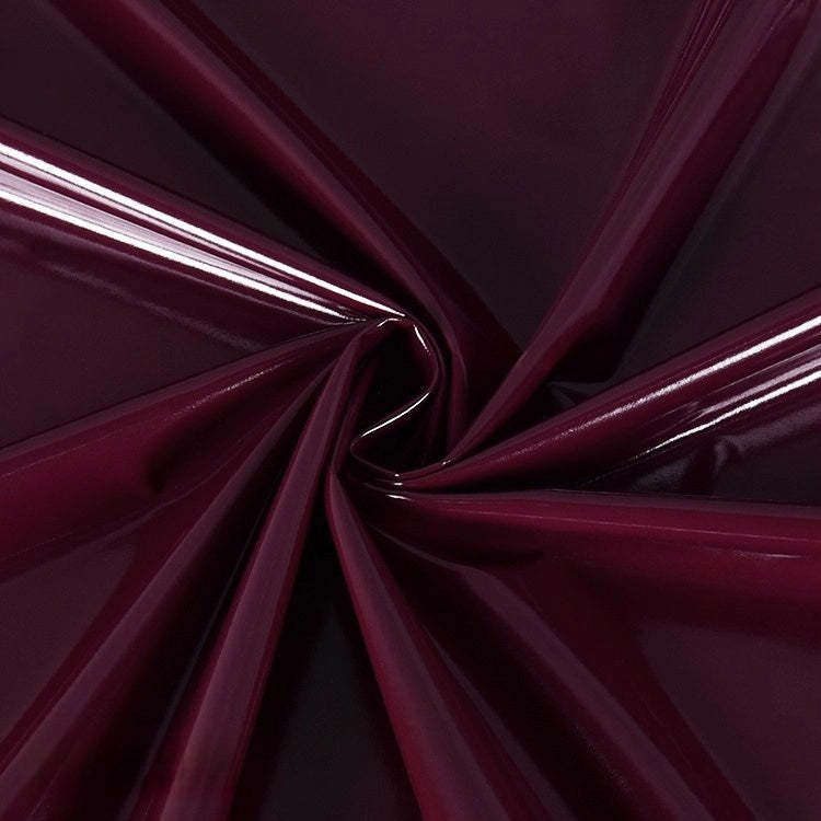 Longan Craft's Glossy Stretch Vinyl Fabric By The Yard features shiny, deep burgundy PU vinyl with a reflective, smooth surface—perfect for making jackets.