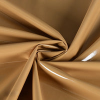 Close-up of Longan Craft Glossy Stretch Vinyl Fabric By The Yard in tan, featuring smooth, shiny PU surface with elegant folds and light reflections. This soft, flexible material is perfect for making jackets and other fashion projects.