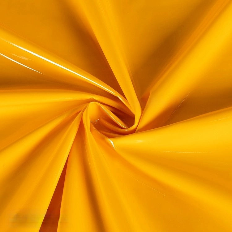 Longan Craft's Glossy Stretch Vinyl Fabric by the yard shines with a bright yellow, mirror-finish surface twisted into a spiral, highlighting its smooth, solid-color PU vinyl—ideal for making jackets.
