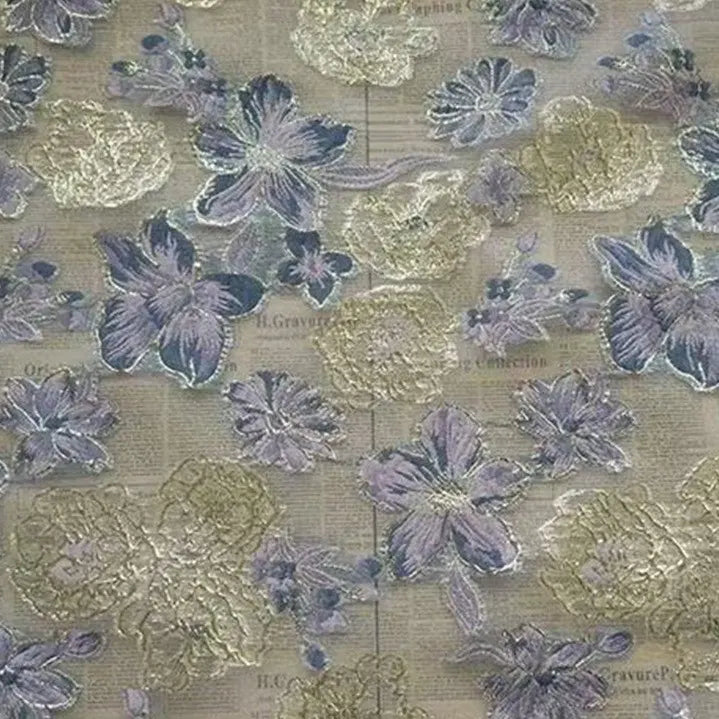A close-up of Longan Craft’s Golden Floral Jacquard Organza Fabric By The Yard shows sheer organza with purple floral patterns and gold embroidery, featuring a background that resembles printed newspaper text.