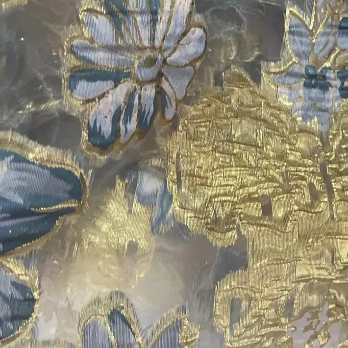 Close-up of Longan Craft’s Golden Floral Jacquard Organza Fabric by the yard, featuring purple and gold floral embroidery on a sheer background—ideal decorative material for dressmaking projects.