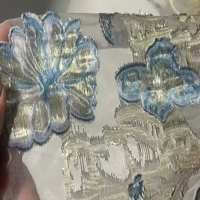 A close-up of Longan Craft’s Golden Floral Jacquard Organza Fabric by the yard, featuring shimmering gold and purple floral embroidery—perfect organza material for dressmaking and highlighting intricate jacquard details.