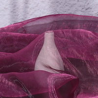 A hand presses against Longan Craft’s Gradient Organza Fabric By The Yard, creating contours beneath the lightweight ombre organza cloth with a textured gray wall behind—an effect popular in modern bridal gowns.