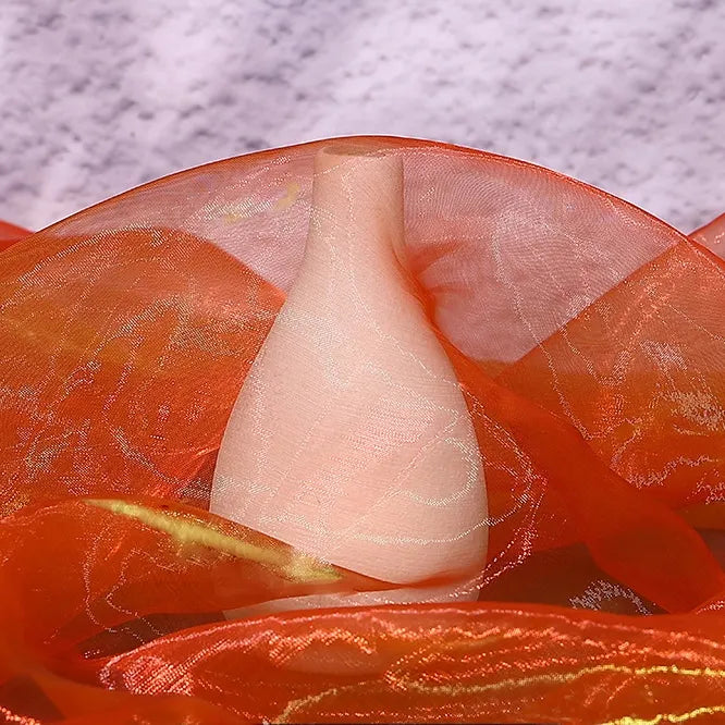 A smooth, pale pink vase is draped in Longan Craft's Gradient Organza Fabric By The Yard, a lightweight ombre organza cloth with shimmering waves, set against a textured light purple background for an elegant touch.